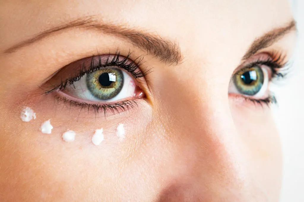 Do eye creams really work? Close up of woman's eye area with dots of eye cream underneath her right eye