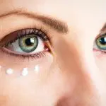 Do eye creams really work? Close up of woman's eye area with dots of eye cream underneath her right eye