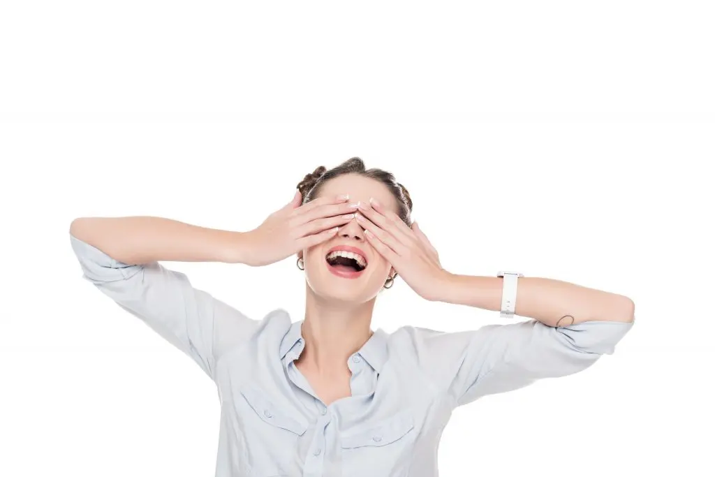10 ways to slow signs of ageing around your eyes without using an eye cream. Image of smiling girl covering eyes with hands isolated on white
