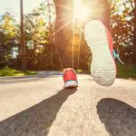 How to start running: Tips for beginner runners. Image of Female runner jogging down the road at sunset