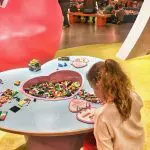 Happy Days: Legoland Discovery Centre Birmingham. Image of a young girl sitting playing with the Lego at a heart shaped table within the Lego Friends area of the centre