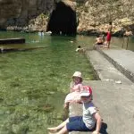 Happy Travels: Where you absolutely should go in Malta. Image of 2 young children paddling their feet at Dwejra Bay Gozo