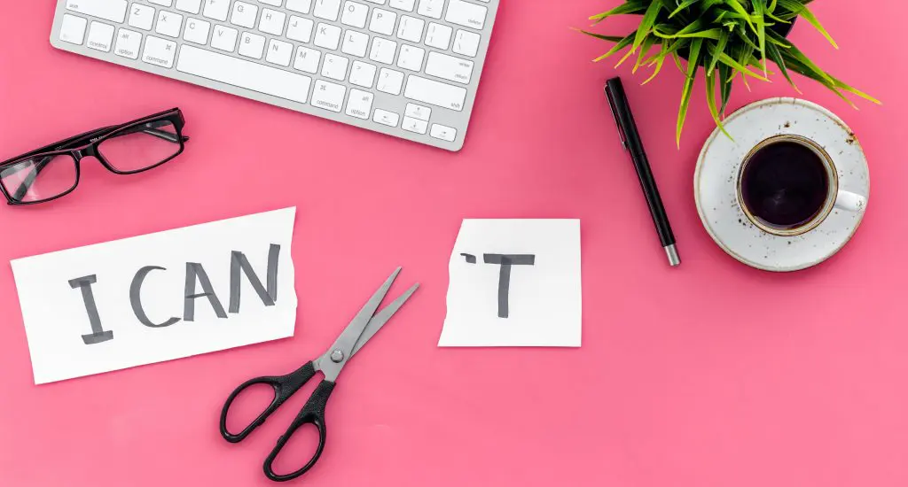 Understanding yourself: How EMDR Therapy helped me develop as a person. Image of a keyboard, glasses, coffee cup and saucer, plant and pen with a pair of scissors cutting through the word I Can't to become I can on a pink background