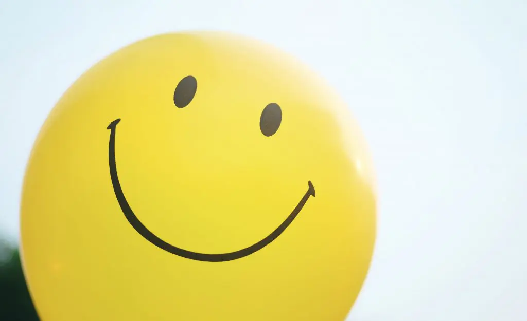 Smile! Everything you need to know (but didn't realise) about smiling. Image of a yellow balloon with a smiling face on it