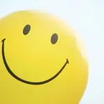 Smile! Everything you need to know (but didn't realise) about smiling. Image of a yellow balloon with a smiling face on it