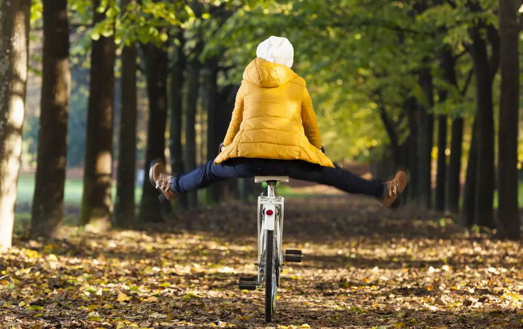 Happy girl riding a bicycle at the park in the Autumn