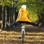 Happy girl riding a bicycle at the park in the Autumn