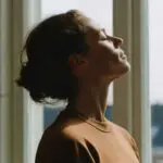 Feature image of a woman in front of a window with her eyes closed, breathing deeply and reseting herself