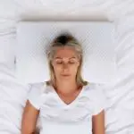 Woman sleeping on her back using an ergonomic pillow designed to support neck alignment and comfortable sleep during menopause