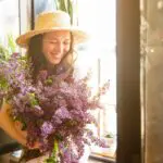 woman happy and smiling by a window holding a bouquet of flowers