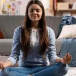 Young girl sitting meditating. Concept of mental health and holistic living