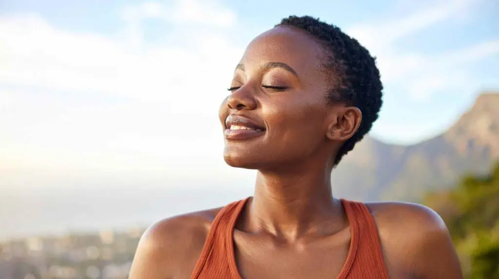 Woman outside in nature with eyes closed happy and peaceful