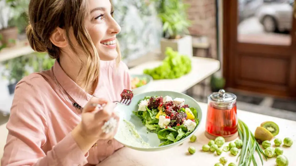 Important to maintain a nutritious diet during a heatwave. A woman enjoys a colourful salad in the summer