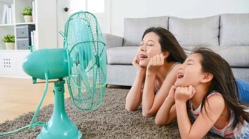 People in front of home fan coping with heatwave fatigue