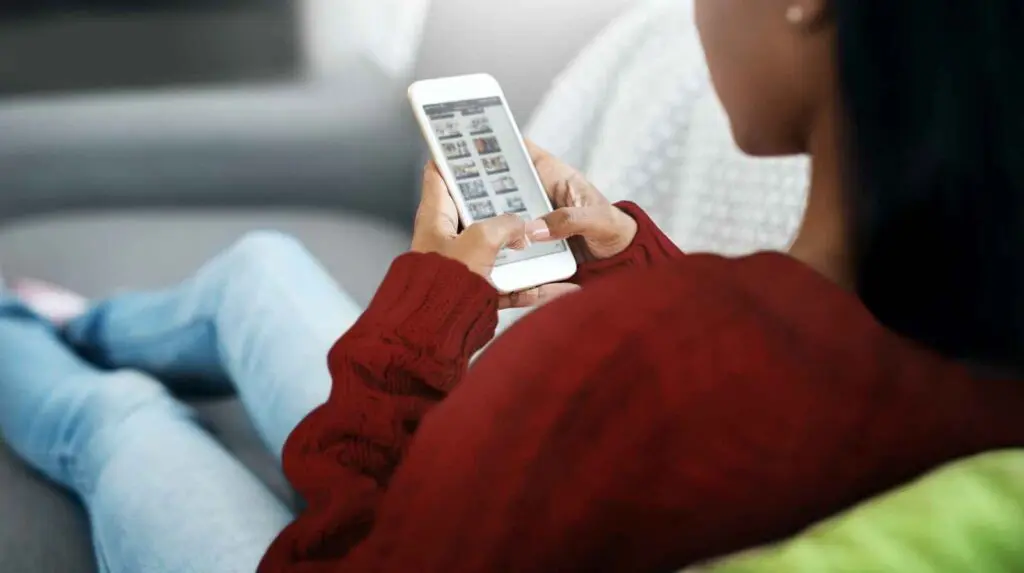 Digital Detox Myth 4 Social Media is Bad for You. A woman sits on a sofa scrolling on her phone