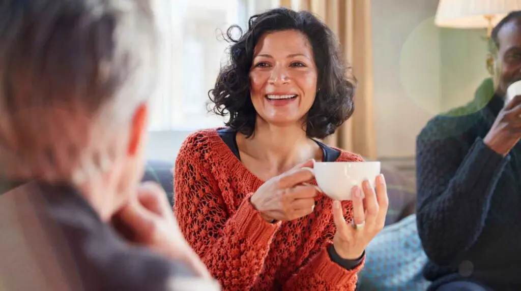 Having community around you is helpful for recovery, a woman sits on a sofa enjoying coffee with her support network