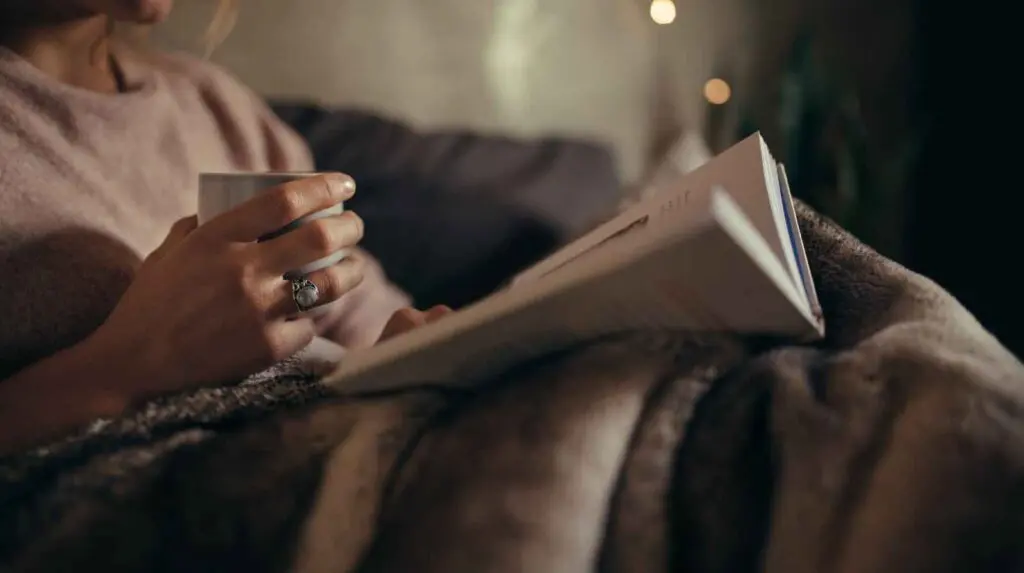woman reading in bed as part of a calm night routine for overactive minds