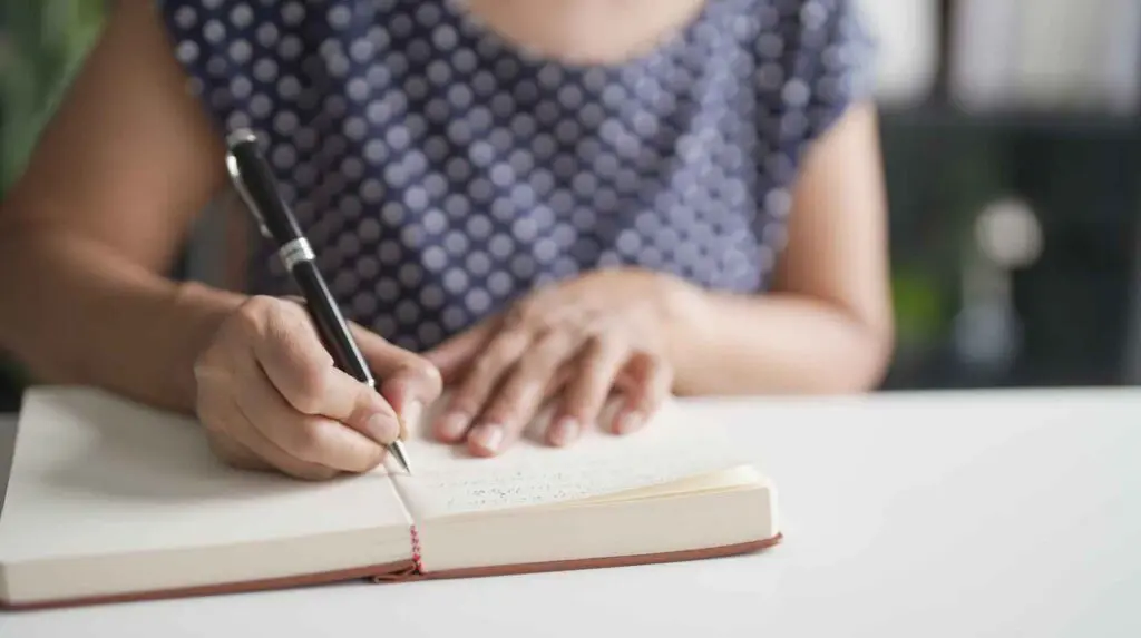 woman sitting and writing a list of questions before her HRT appointment