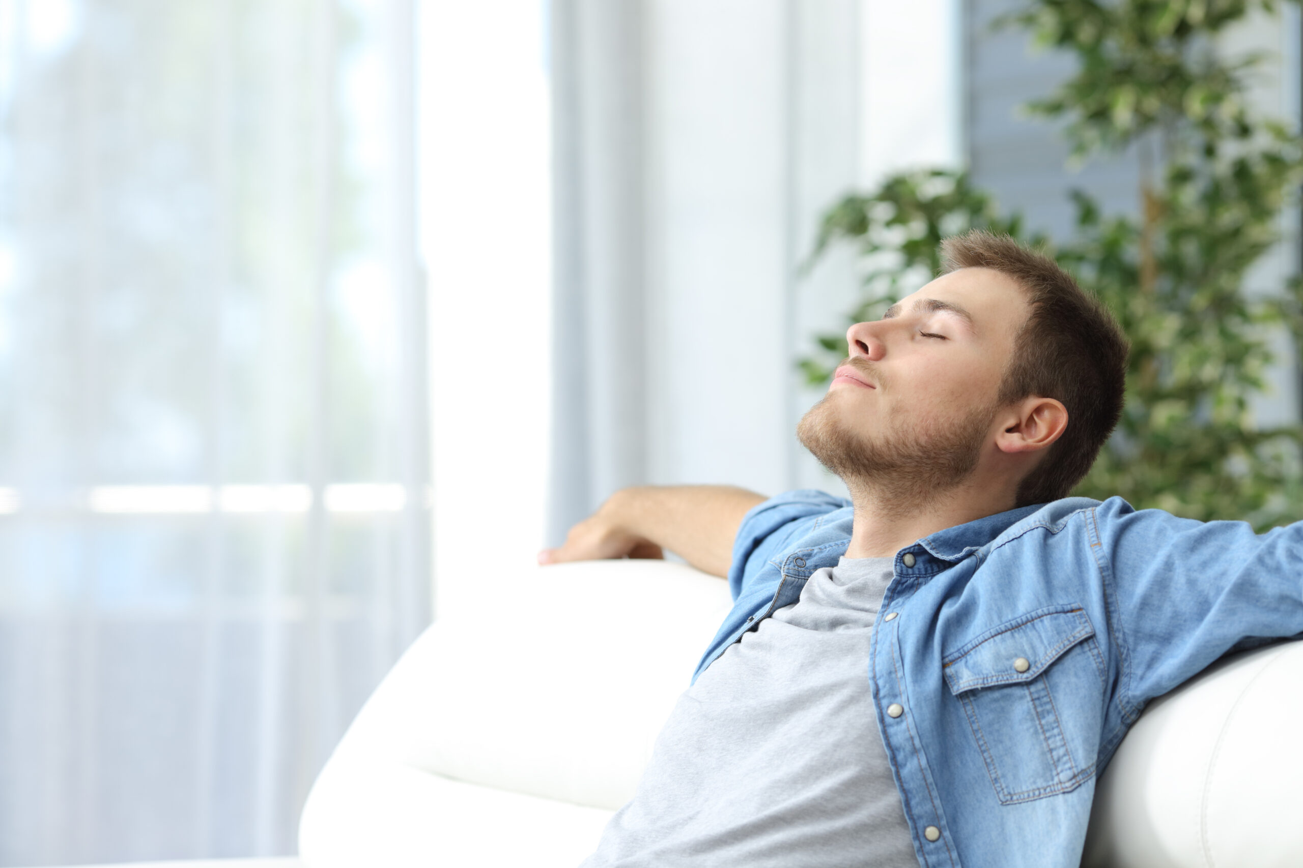Being mindful - Is mindfulness for you? Image of young man relaxing on a sofa with his eyes closed