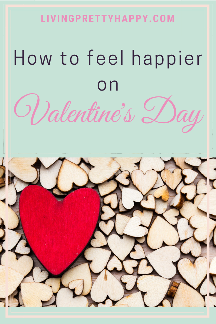 How to feel happier on Valentine's Day. Pinterest graphic displaying post title on a background image of lots of little wooden hearts with one big red wooden heart on top. Livingprettyhappy.com