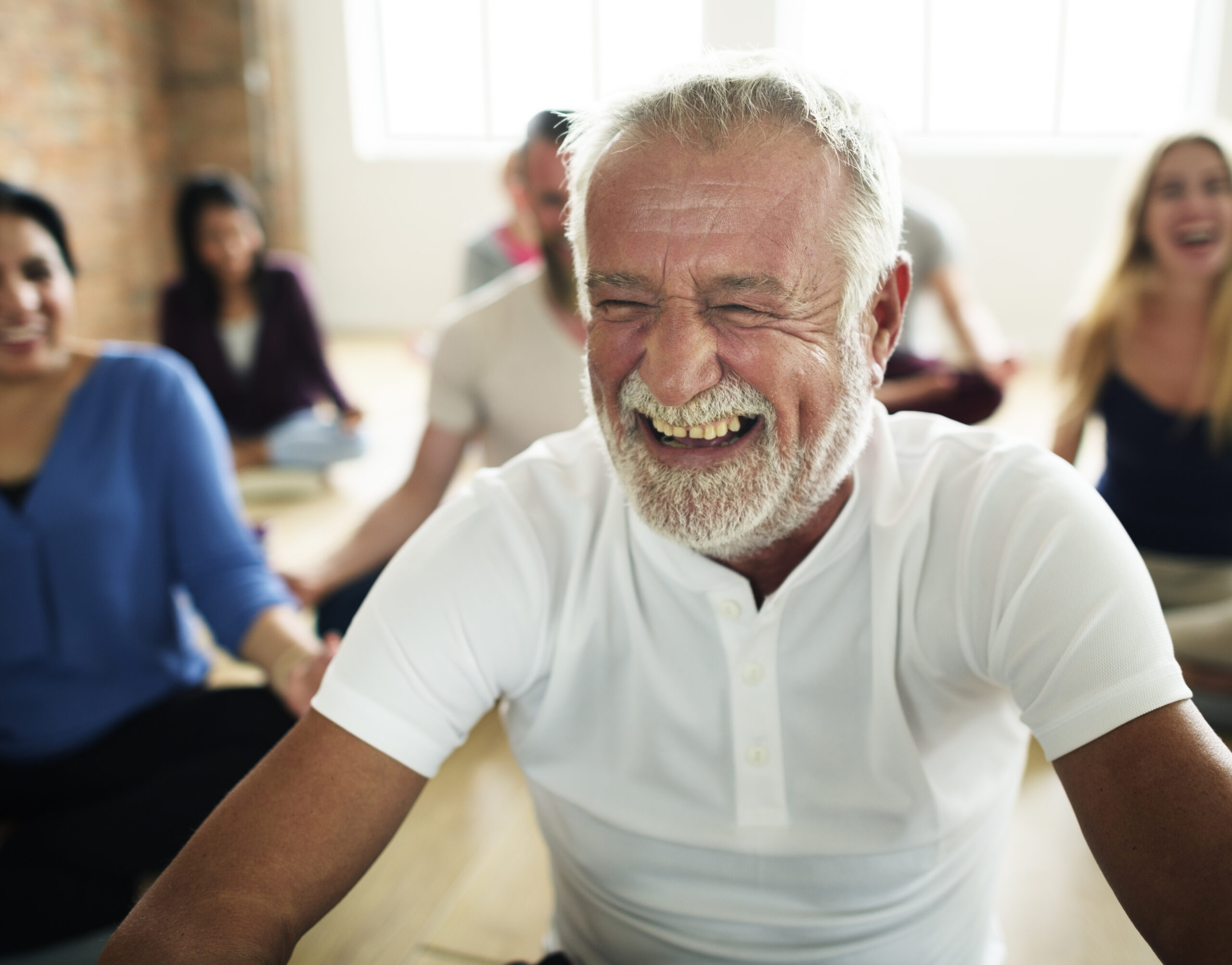 5 Ways exercise makes you happy. Image of a relaxed smiling older gentleman taking part in a yoga meditation class