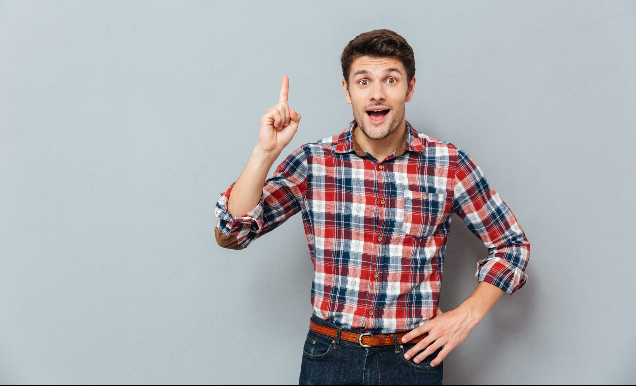Exercise Hacks: How to be fitter without really trying. Image of Happy casual man standing up pointing upwards over grey background