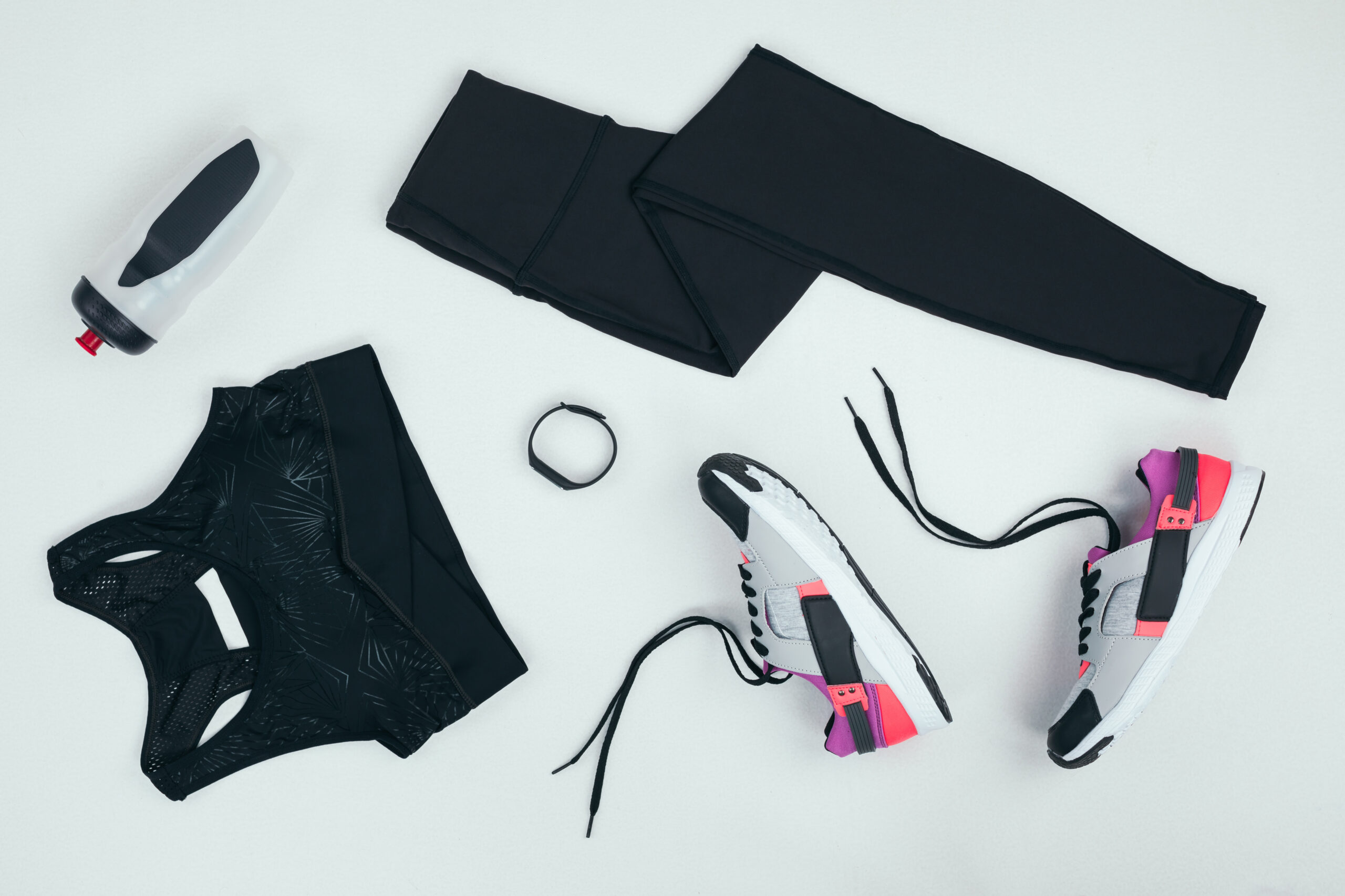 How to keep your running motivation. Image of flat lay with sportswear with sneakers, fitness tracker and sports bottle isolated on grey.