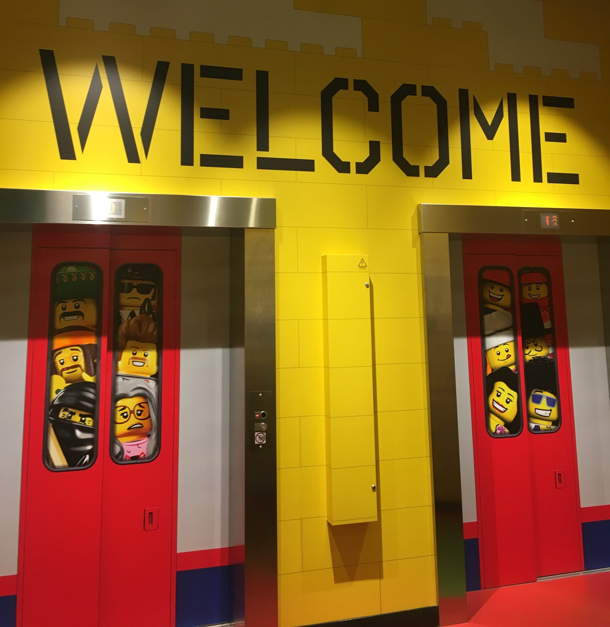 Happy Days: Legoland Discovery Centre Birmingham. Image 2 lifts displaying pictures of Lego characters with the words WELCOME above it at Legoland Discovery Centre Birmingham