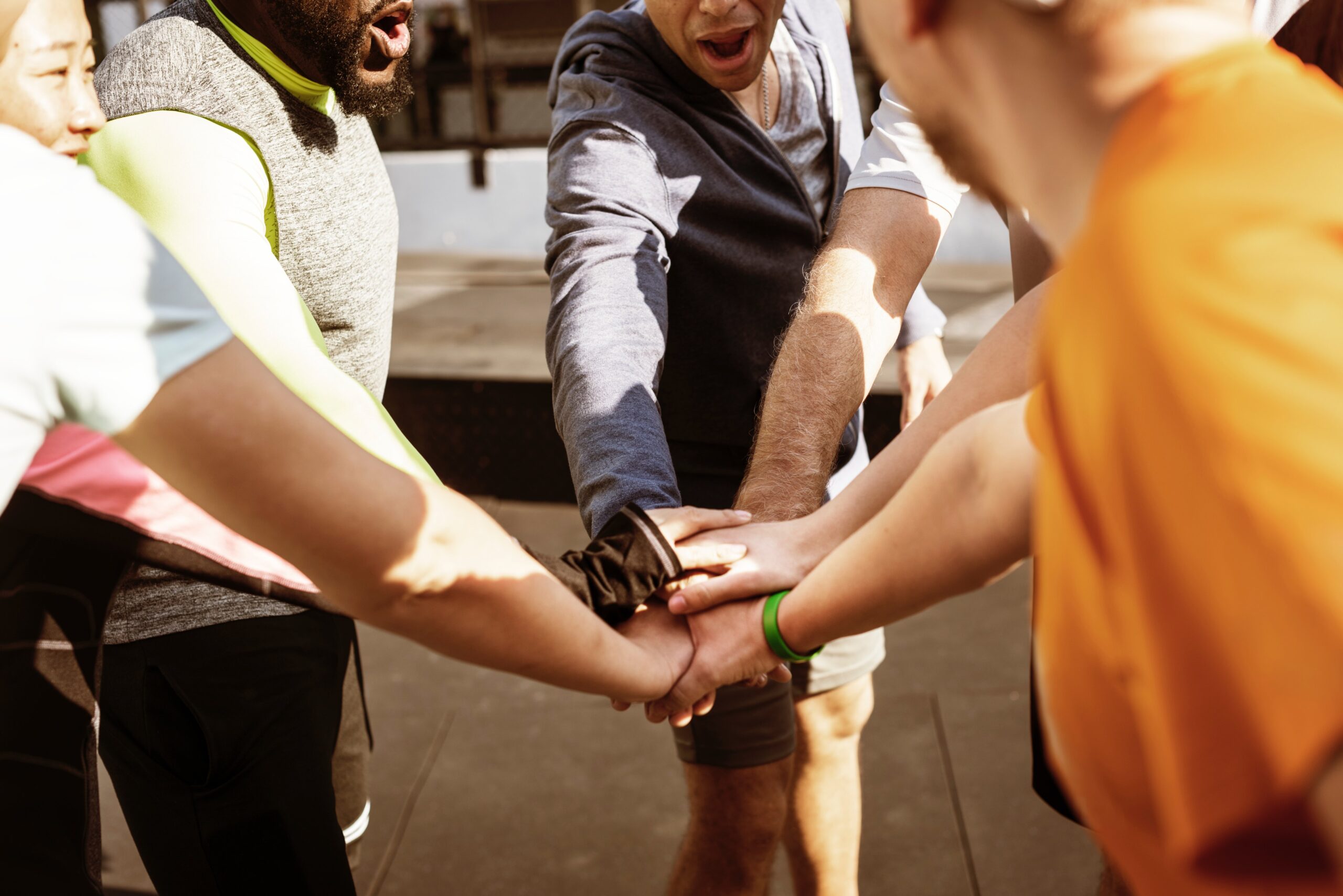How to keep your running motivation. Image of a group of people putting their hands into a circle to celebrate a work out