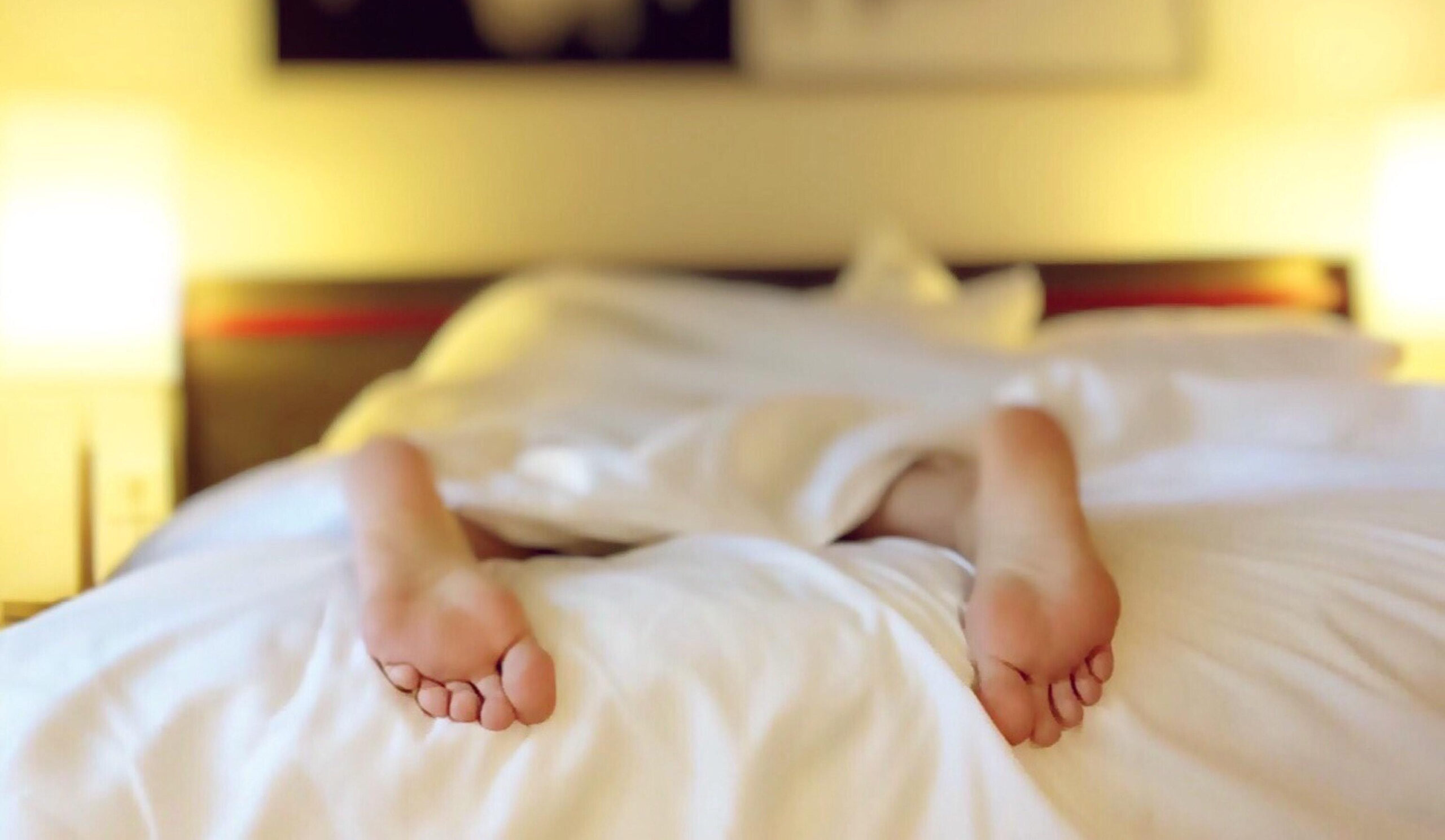 5 Useful ways mindfulness helps in your everyday life. Image of a person's bare feet protruding out of the end of the bed