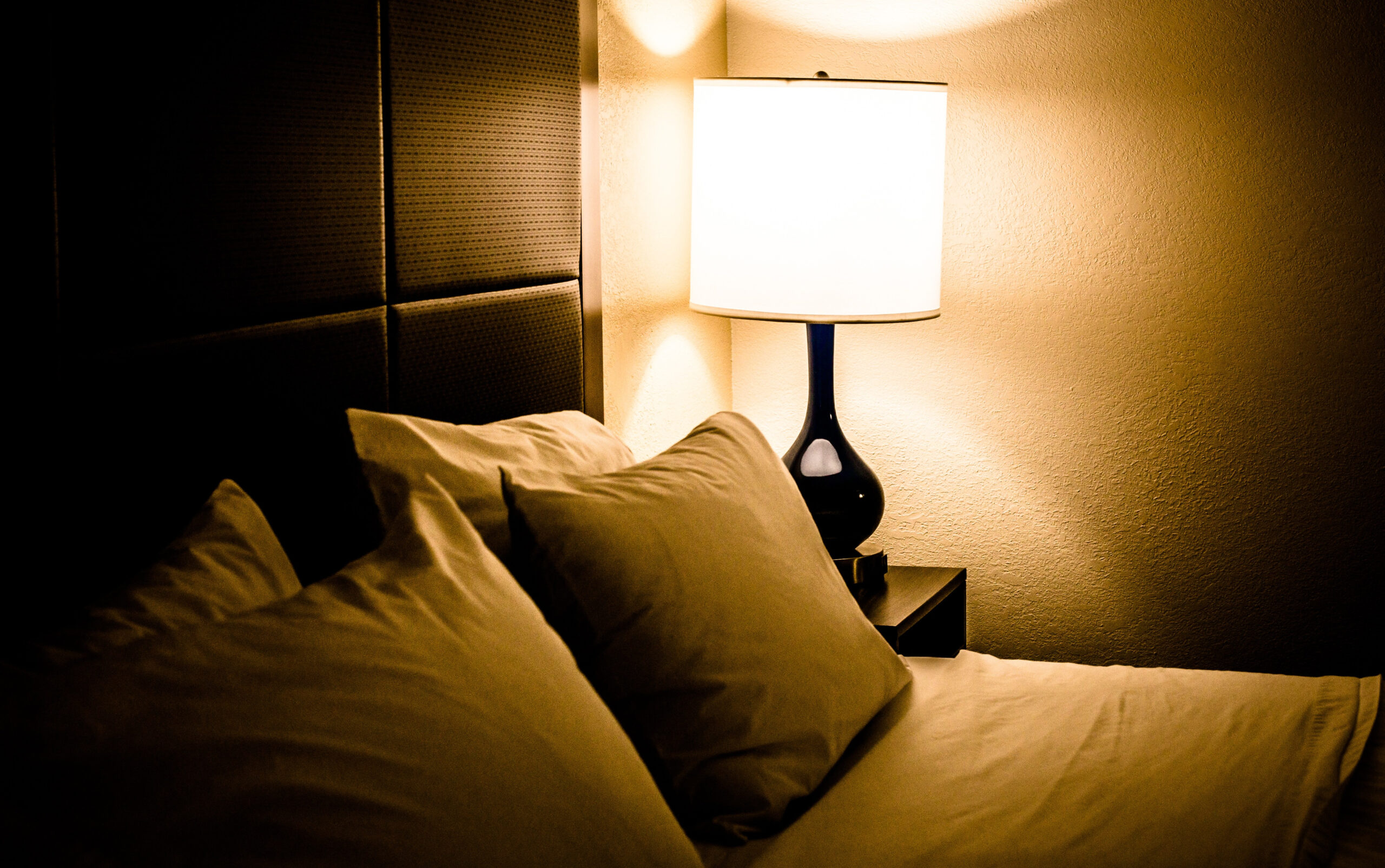 Sleep well: How to win at sleeping! (and why you should want to) How to get a better night's sleep Image of a darkened bedroom with a bedside lamp providing light