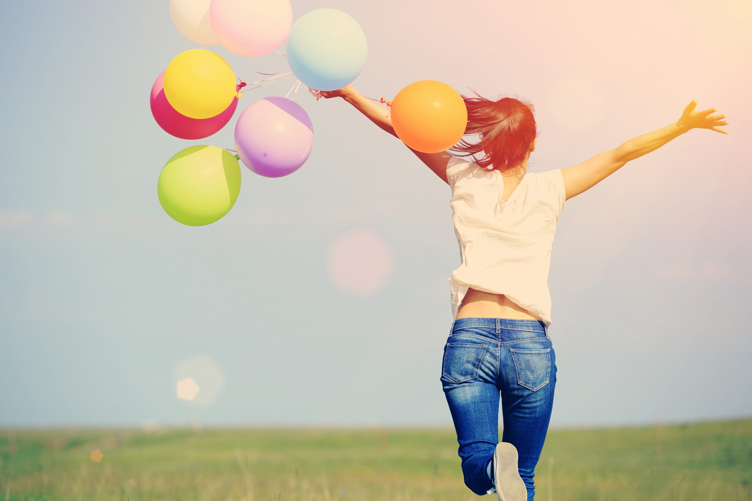 Catastrophe to calmness: A technique to calm your worrying thoughts. How to stop catastrophizing. Image of your woman running through a field holding a bunch of balloons