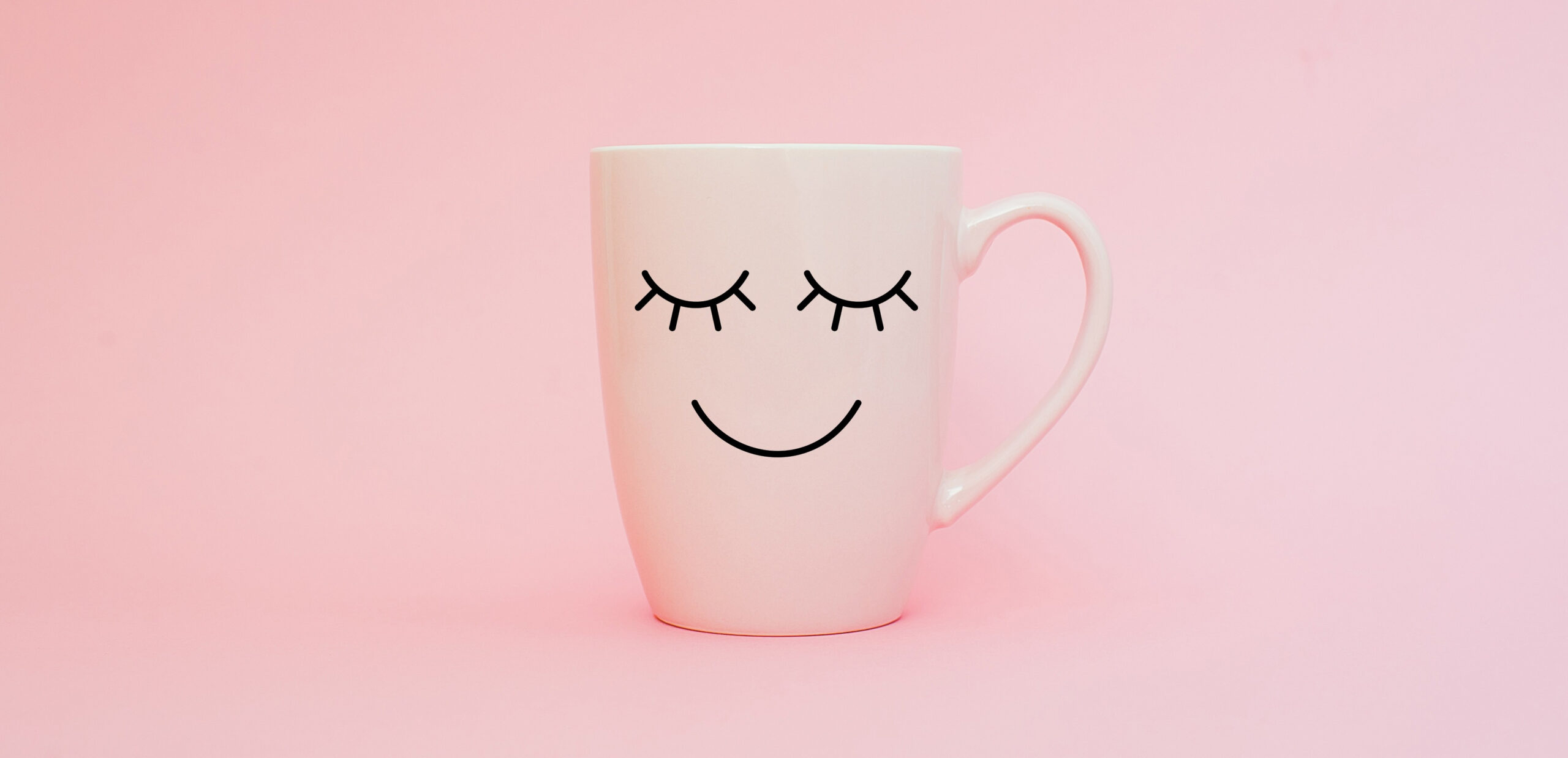 Smile! Everything you need to know (but didn't realise) about smiling. Image of a white mug with a smiling face drawn on against a pink background